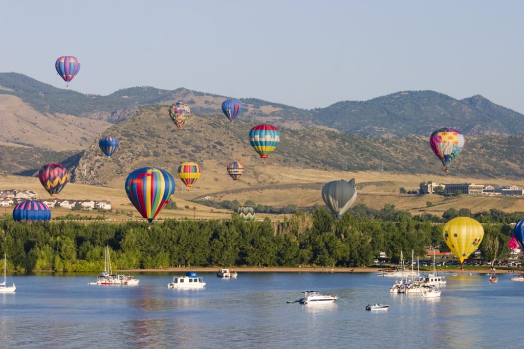 Hot air balloons rising over the Colorado mountains at sunrise